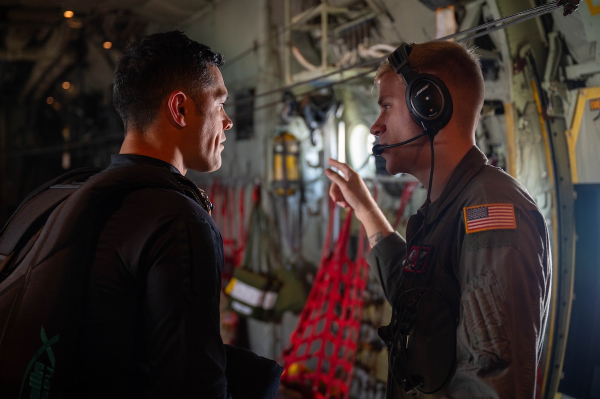 A USAF Loadmaster speaks with a NZDF a member of the Kiwi Blue Parachute Team on a C-130J Super Hercules.