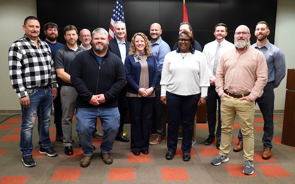 Group of 15 men and women standing in conference room.