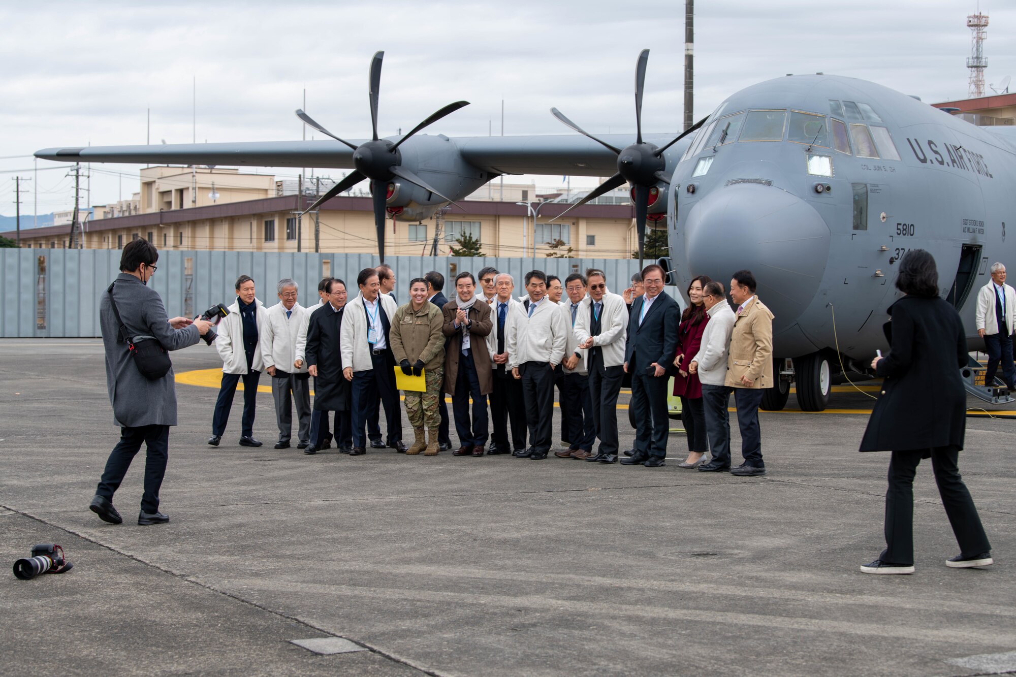 Members of the Korea Peace Foundation prepare for a group photo in front of a C-130J Super Hercules at Yokota Air Base, Japan.