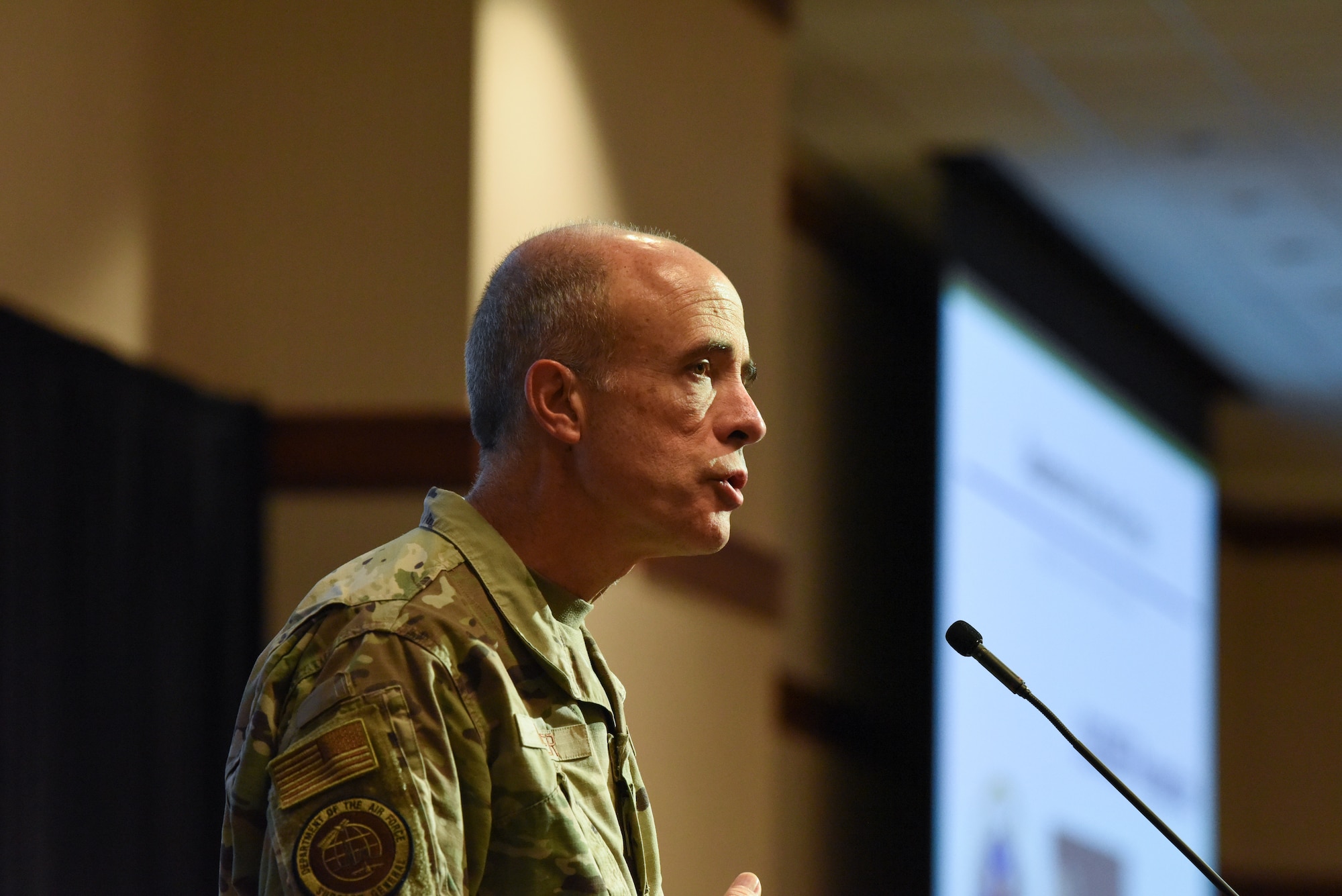 Image of an Airman speaking at a podium.