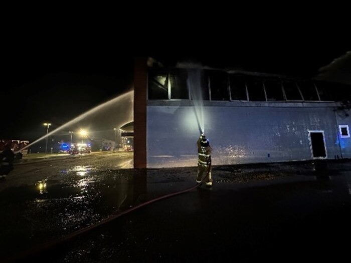 U.S. Air Force Senior Airman Griffin Maharrey, 31st Civil Engineer Squadron firefighter, sprays water onto a warehouse fire.