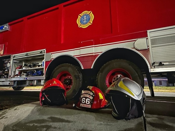 Helmets from multiple fire departments are displayed in front of a fire truck