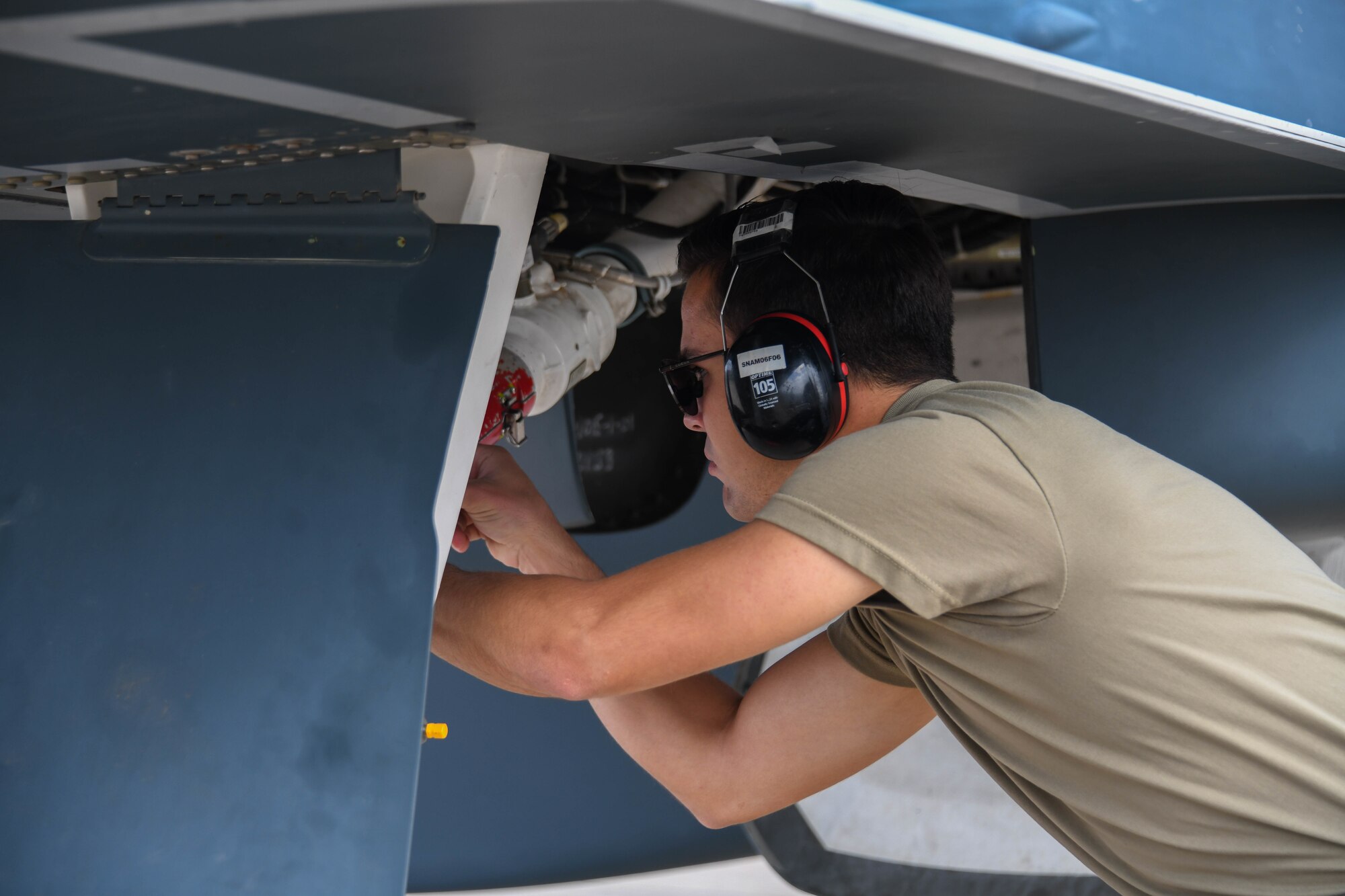 A man in a military uniform works on a aircrafts wing.