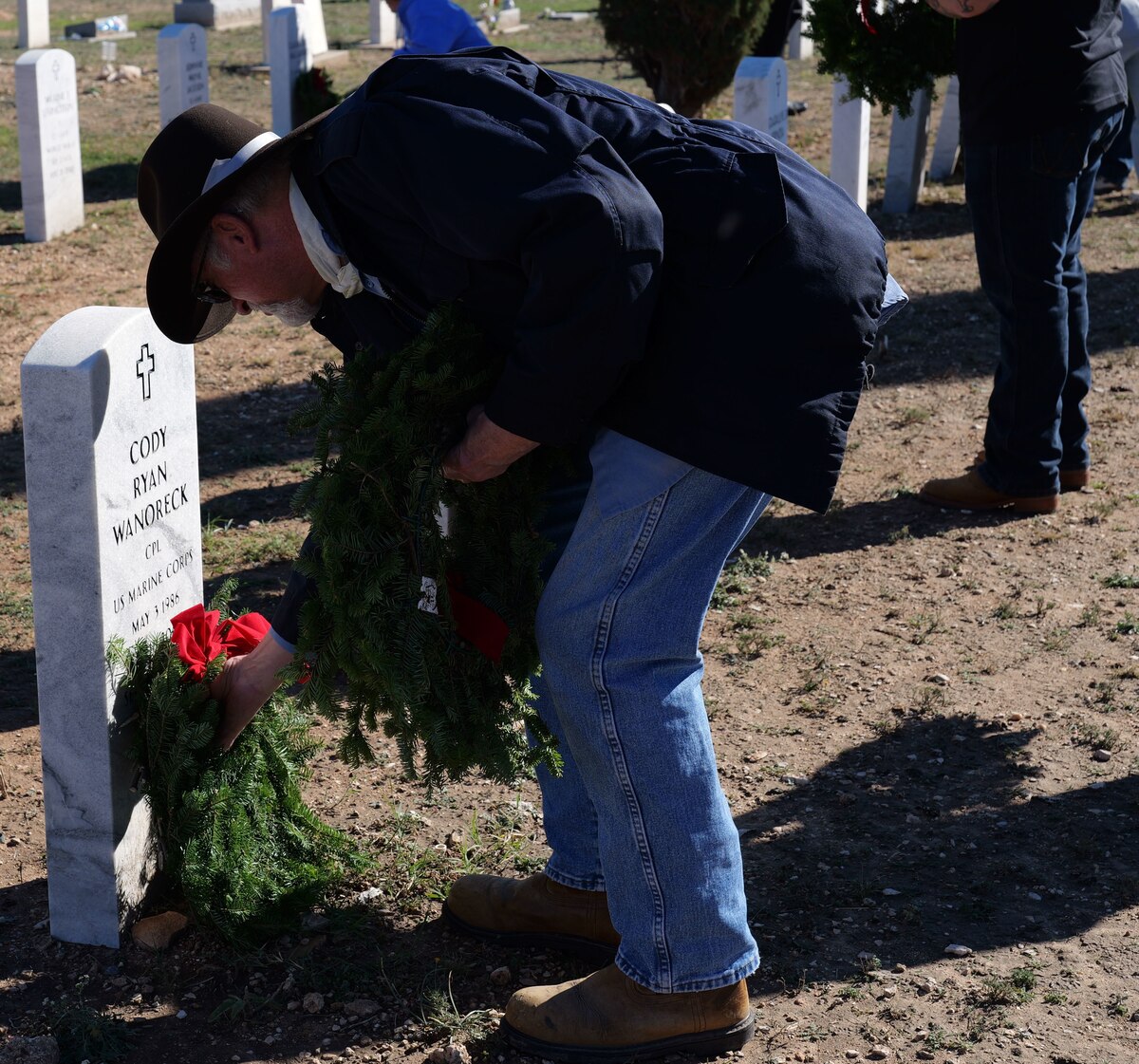 A member of the San Angelo Community places a wreath after the Wreaths Across America ceremony at San Angelo, Texas, Dec. 16, 2023. Following the ceremony, over 300 wreaths were placed at the headstones of deceased military members. (U.S. Air Force photo by Staff Sgt. Nathan Call)