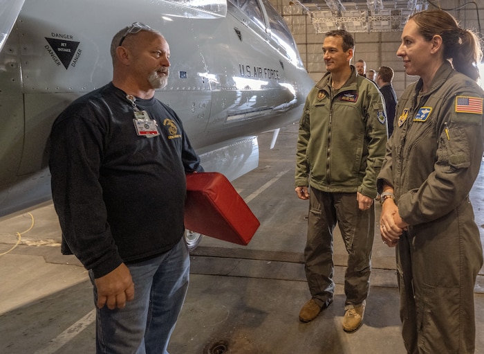 A U.S. Air Force brigadier general, a deputy commander, and flight test engineer talk in front of the T-7 Red Hawk.