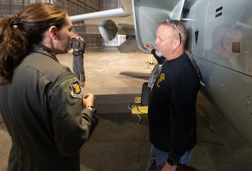A flight mechanic and deputy commander talk near the intake of a T-7 Red Hawk aircraft.