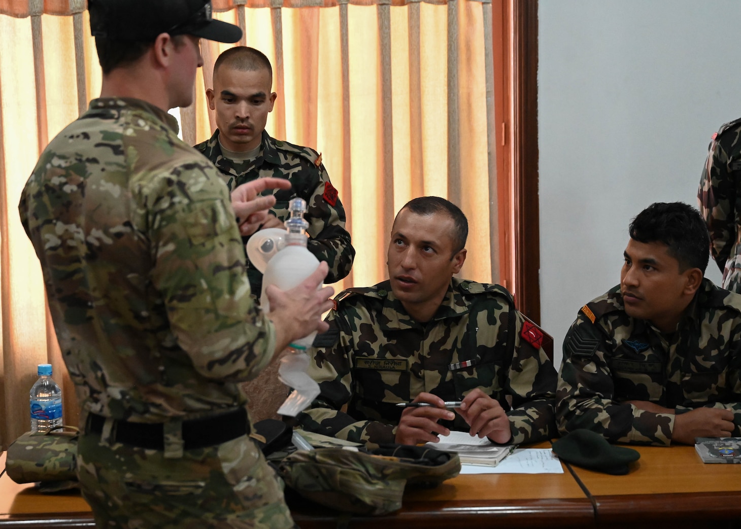 A U.S. Naval Special Warfare operator discusses tactical combat casualty care procedures with members of the Nepali Army and Nepali Special Operations Force (SOF) Brigade during a subject matter expert exchange at Ganesh Kashya, the Nepali Army headquarters in Kathmandu, Nepal. Naval Special Warfare trains with forces worldwide to improve and further specialize skills required to conduct missions and respond to crises.