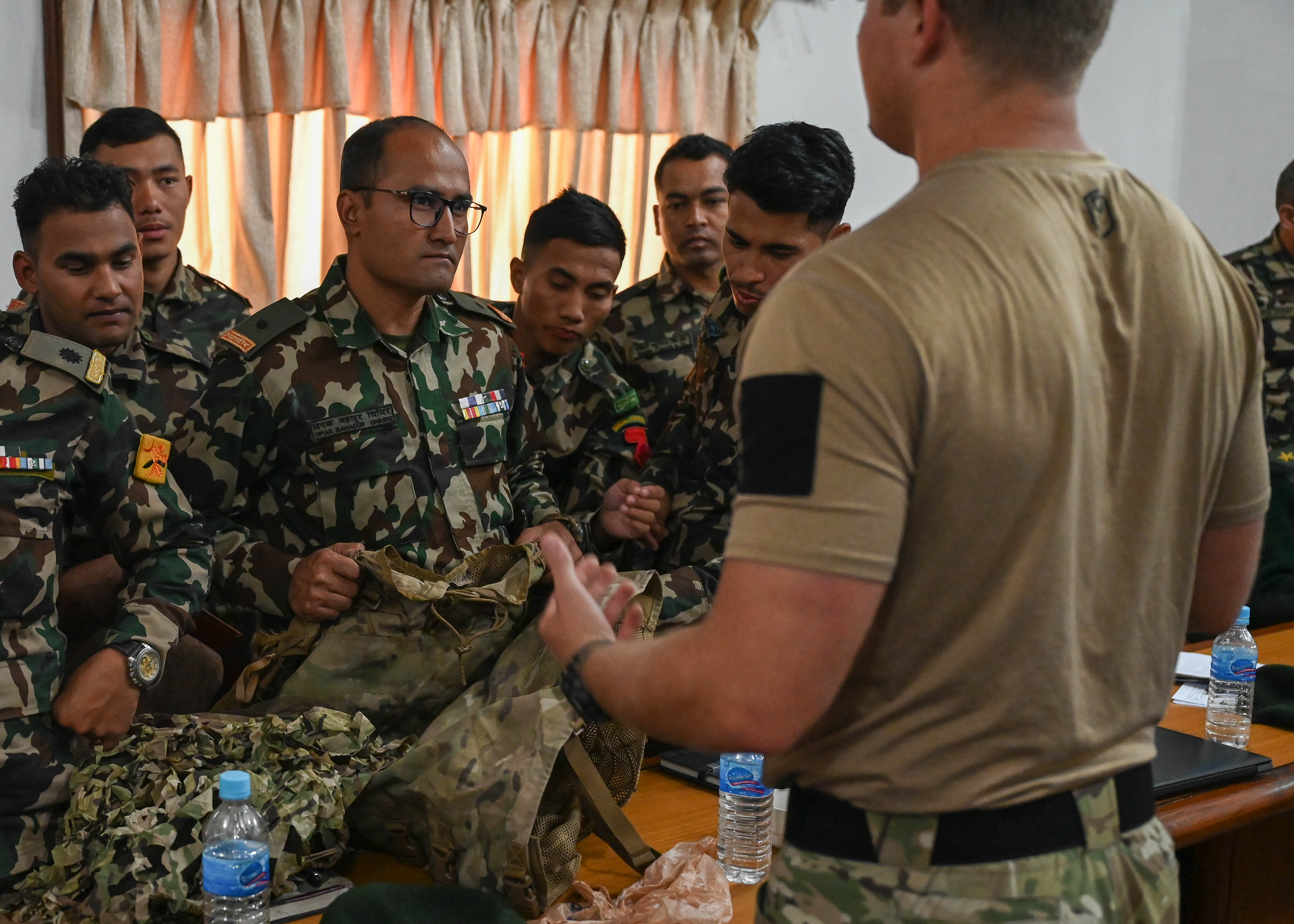 A U.S. Naval special warfare operator discusses camouflage techniques with members of the Nepali Army and Nepali Special Operations Force (SOF) Brigade during a subject matter expert exchange at Ganesh Kashya, the Nepali Army headquarters in Kathmandu, Nepal. Naval Special Warfare trains with forces worldwide to improve and further specialize skills required to conduct missions and respond to crises.