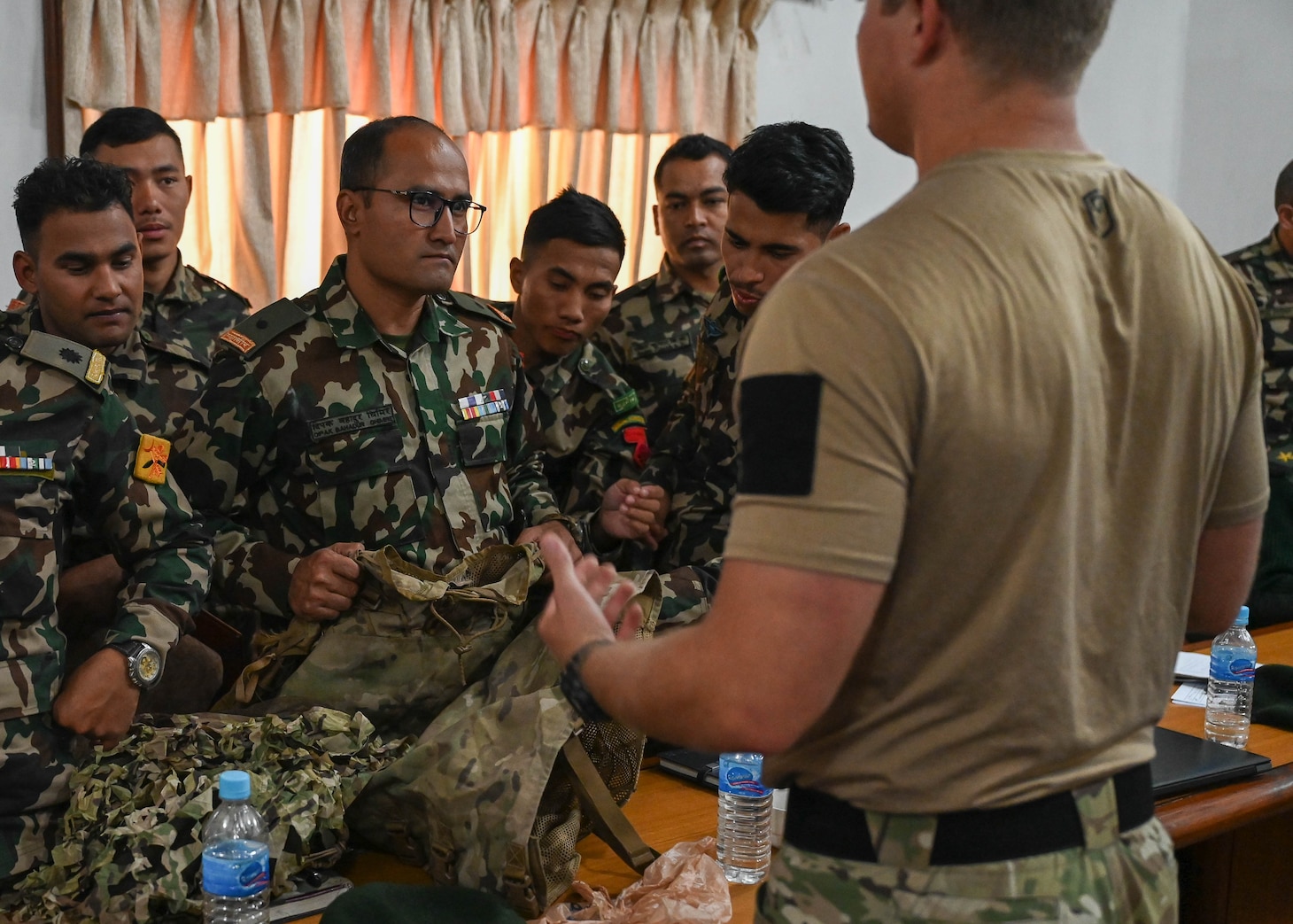 A U.S. Naval special warfare operator discusses camouflage techniques with members of the Nepali Army and Nepali Special Operations Force (SOF) Brigade during a subject matter expert exchange at Ganesh Kashya, the Nepali Army headquarters in Kathmandu, Nepal. Naval Special Warfare trains with forces worldwide to improve and further specialize skills required to conduct missions and respond to crises.