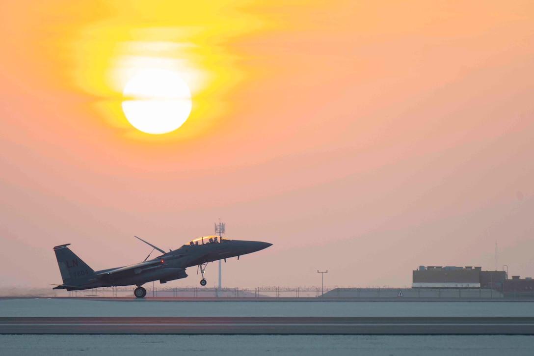 An aircraft takes off on a runway as the sun shines behind.