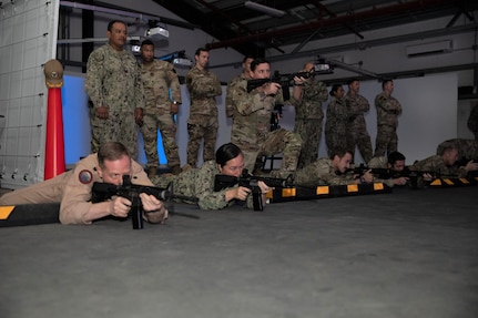 Sailors practice shooting weapons on a virtual range.