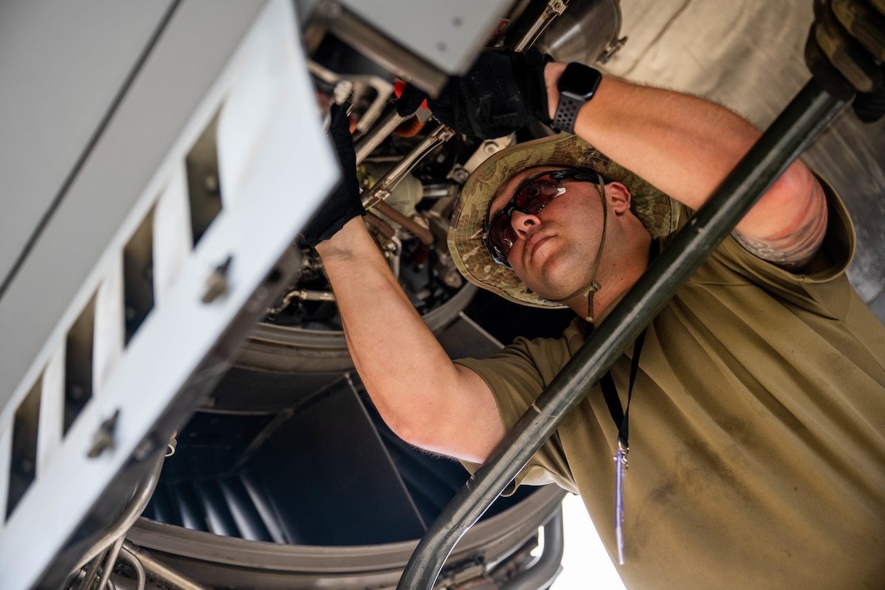 An airman inspects the engine of a military aircraft.