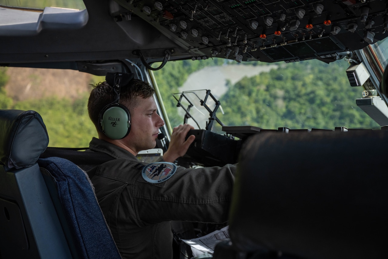 An airman sits in the cockpit of a military aircraft.