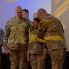 A group of U.S. Army soldiers stand on a stage