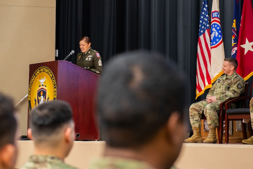 A female U.S. Army soldier stands at a podium during a ceremony