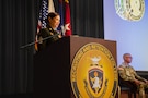 A female U.S. Army soldier stands at a podium during a ceremony