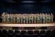 Large group of U.S. Army soldiers stand on stage after a graduation and promotion ceremony