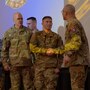 Group of U.S. Army soldiers stand on a stage during a ceremony