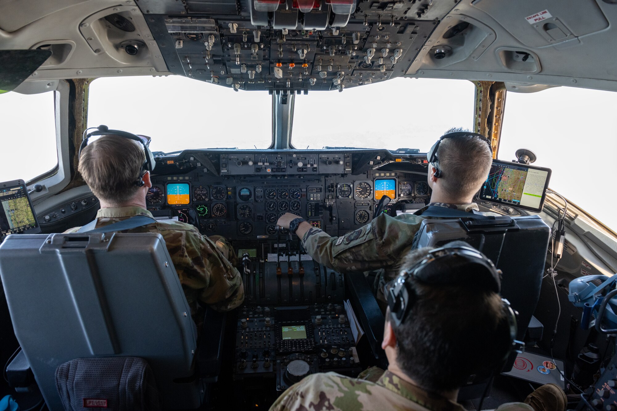 A pilot, copilot and flight engineer sit in a KC-10 cockpit