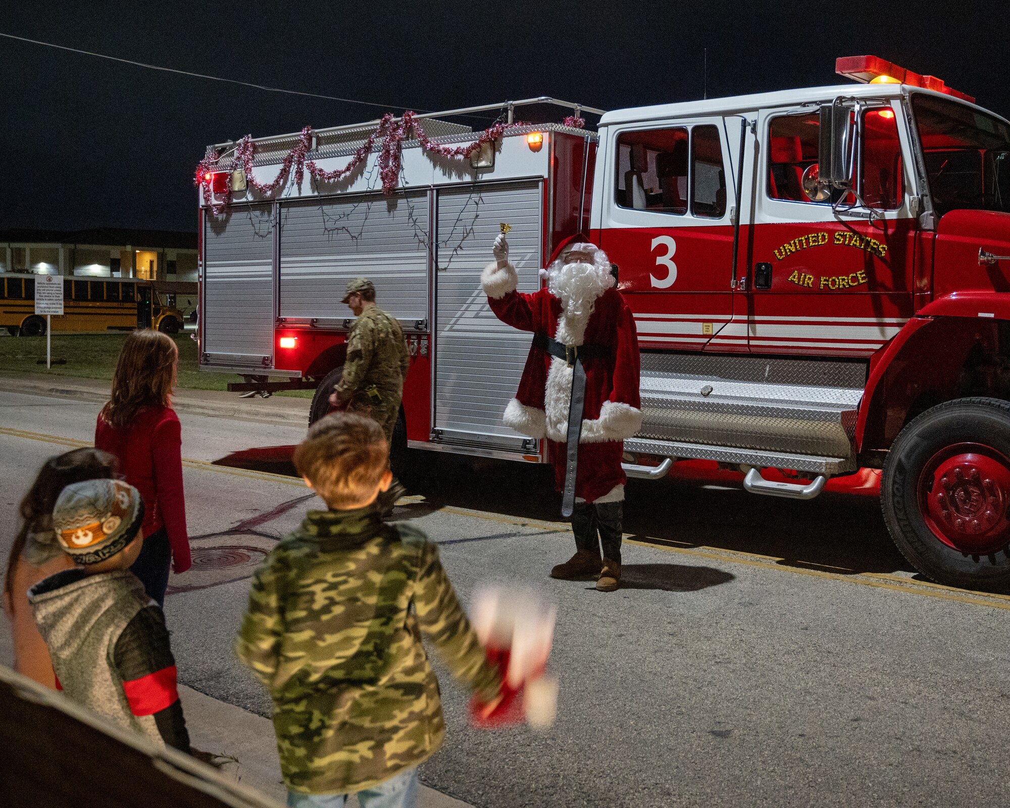 Santa comes out of a firetruck to greet children at the tree lighting ceremony at Laughlin Air Force Base, Texas, Nov. 29, 2023. After the ceremony children and their families were able to go and have "Dinner with Santa" at Club XL. (U.S. Air Force photo by Staff Sgt. Nicholas Larsen)