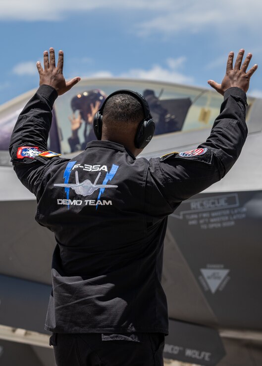 A photo of an F-35 crew chief standing in front of a jet