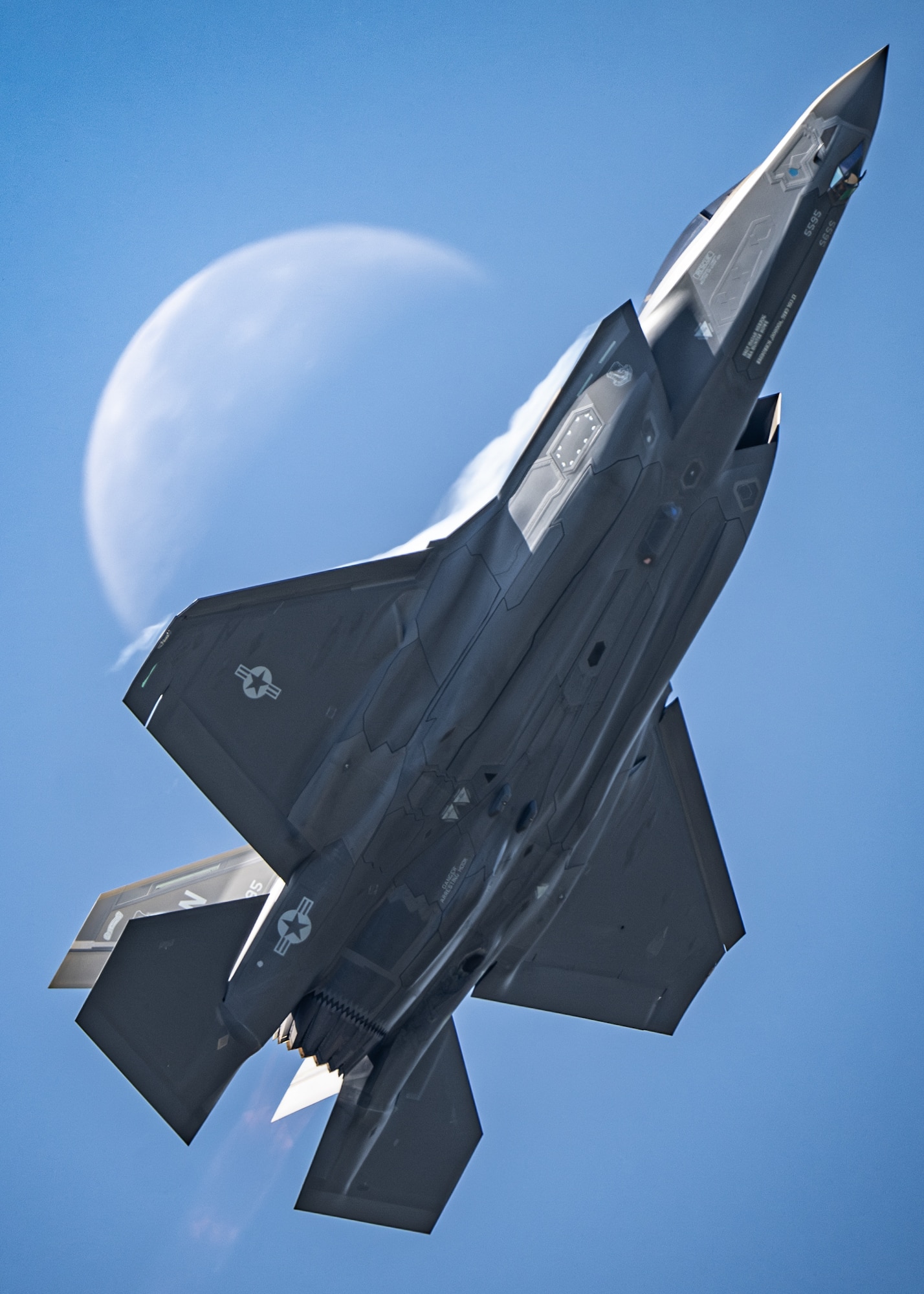 An F-35 flying in front of a crescent moon