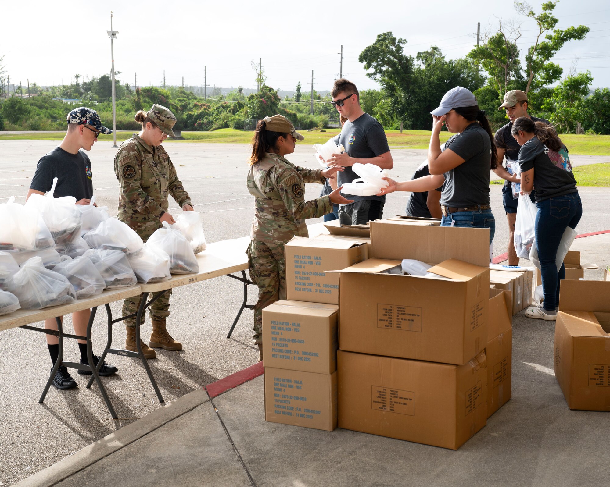 U.S. Air Force members assigned to the 734th Air Mobility Squadron, bag food during a volunteer event in Dededo, Guam, December 15, 2023.  The 734 AMS volunteered to help Dededo as part of the Sister Village Sister Squadron program. They collected food, toiletry, and lifesaving equipment donations and helped hand them out to local families. (U.S. Air Force photo by Airman 1st Class Spencer Perkins)