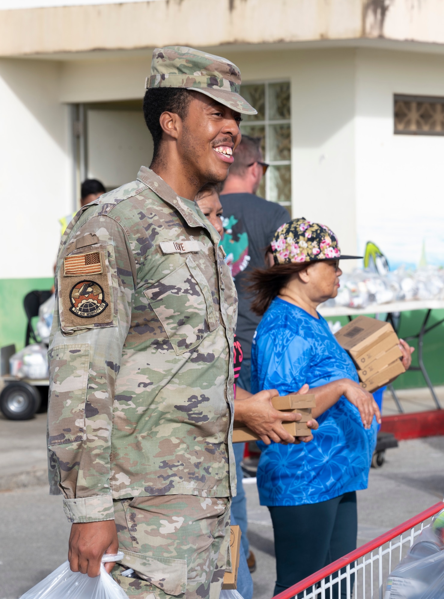 U.S. Air Force Staff Sgt. Christian Love, 734th Air Mobility Squadron commander support staff noncommissioned officer in charge, waits to give food to a local family at a volunteer event in Dededo, Guam, December 15, 2023.  The 734 AMS volunteered to help Dededo as part of the Sister Village Sister Squadron program. They collected food, toiletry, and lifesaving equipment donations and helped hand them out to local families. (U.S. Air Force photo by Airman 1st Class Spencer Perkins)