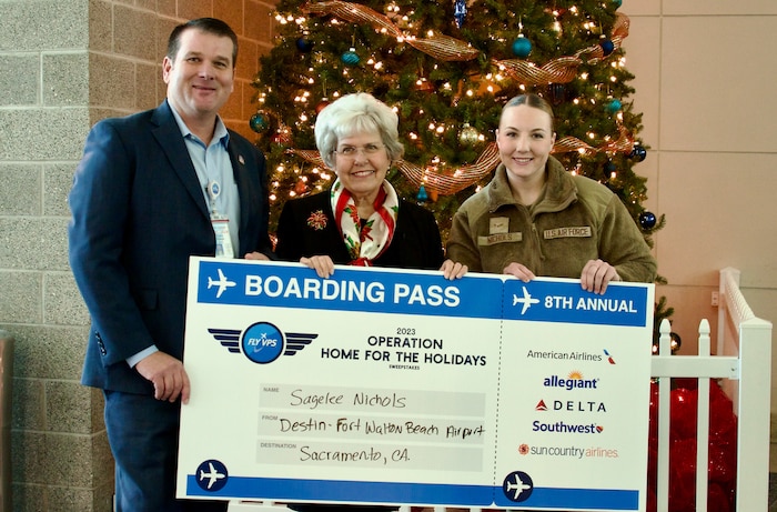 The VPS airport director and Okaloosa County commissioner hold a large boarding pass with the winner.
