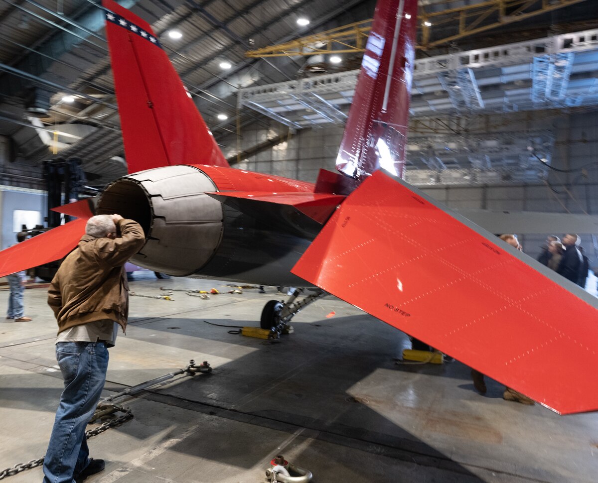 A civilian looks inside the T-7 Red Hawk exhaust nozzle.