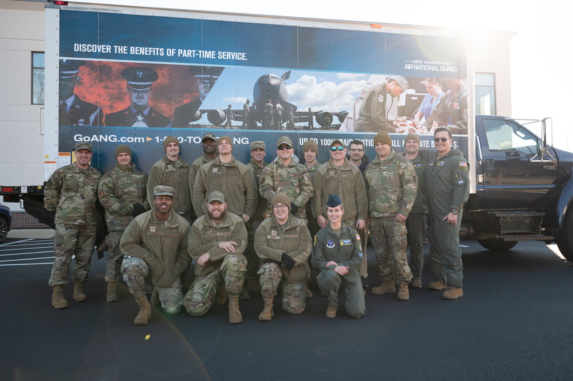Airman stand in front of a box truck.