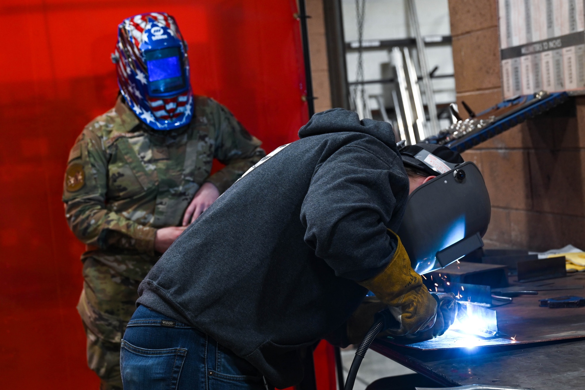 Senior Airman Mikayla Proctor, 28th Maintenance Squadron aircraft metals technology journeyman, supervises a student from Douglas High School as he welds two pieces of metal together at Ellsworth Air Force Base, South Dakota, Dec. 12, 2023.
