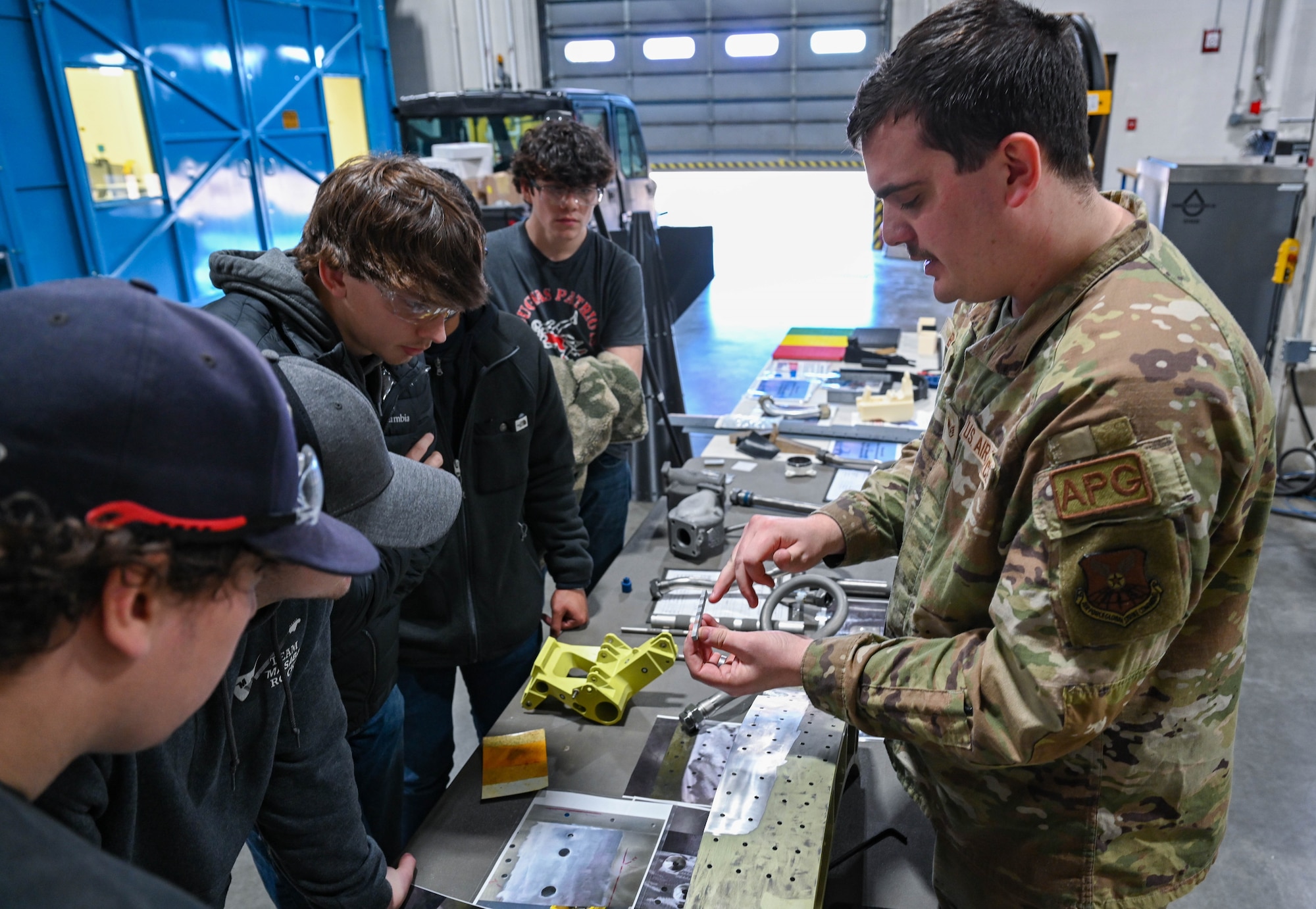 Staff Sgt. Gunner Berg, 28th Maintenance Group additive manufacturing technician, shows students from Douglas High School a 6061-aluminum alloy sample at Ellsworth Air Force Base, South Dakota, Dec. 12, 2023.