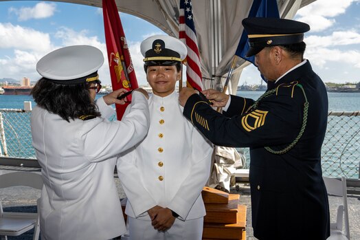  Midshipman 1st Class Mahinalani Vongsy receives her ensign shoulder boards from her parents during a commissioning ceremony aboard the Battleship Missouri Memorial.