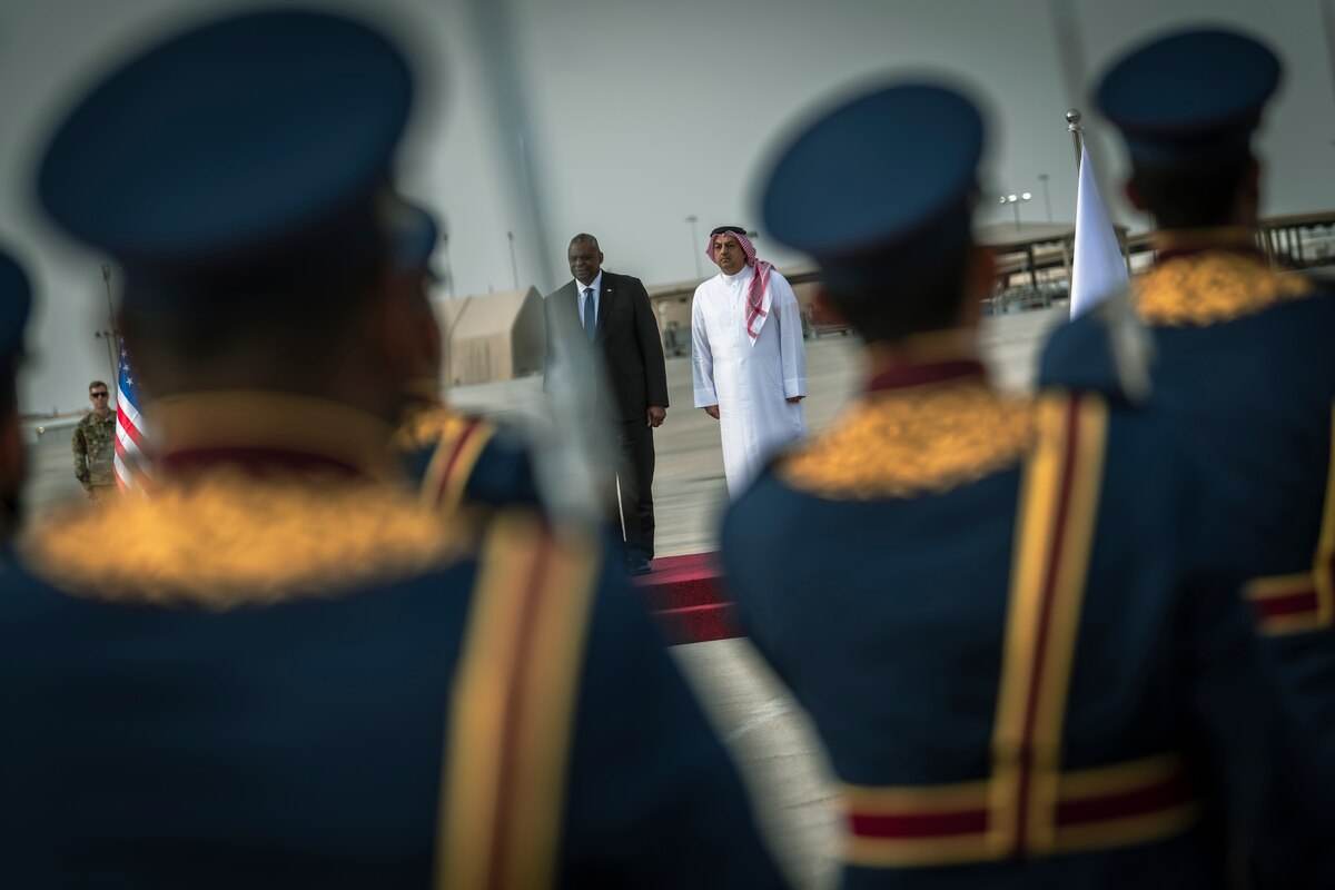 Two men stand side by side before members of a foreign military.