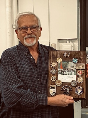 Man holds plaque with coins attached