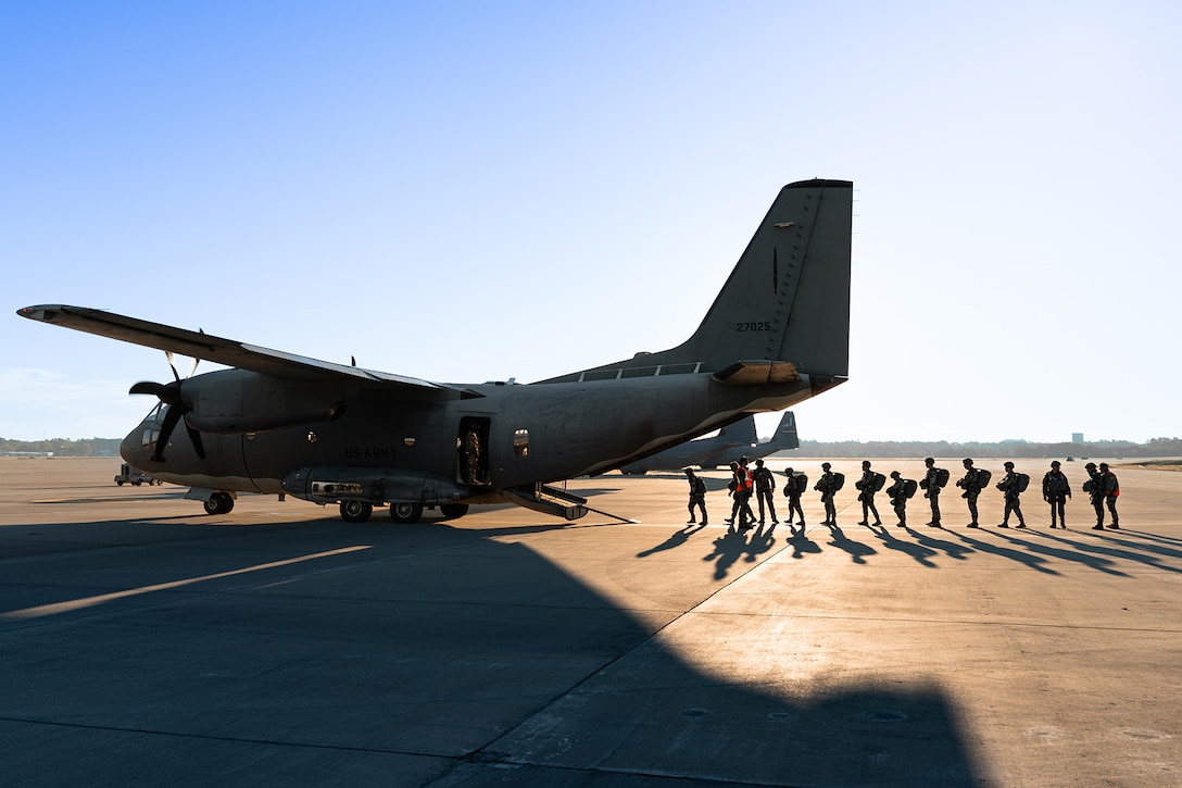 Soldiers line up to board an aircraft.
