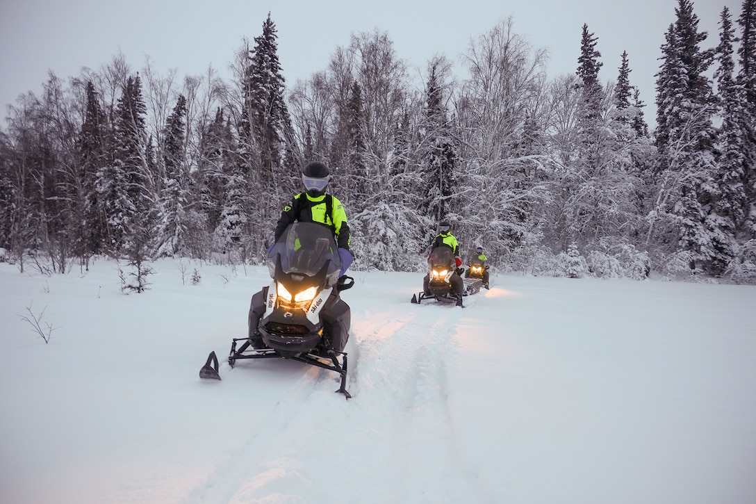 Soldiers ride snow machines and sleds in the snow filled with toys.