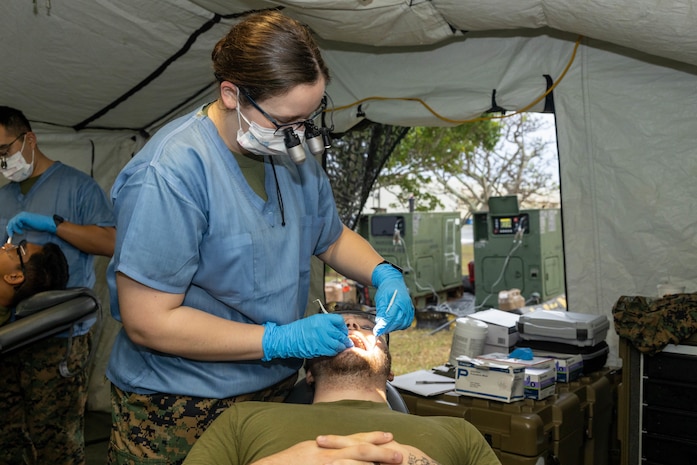 U.S. Navy Lt. Kelsey Freeman, a dental officer with 3rd Dental Battalion, 3rd Marine Logistics Group (3rd MLG), performs a dental examination on Hospital Corpsman 3rd Class Kaleb Peacock, a corpsman with 3rd Medical Battalion, 3rd MLG, during the SHIKA-X field dentistry exercise on Camp Hansen, Okinawa, Japan, Dec. 13, 2023. 3rd Dental Battalion conducted a field training exercise to gain proficiency in executing dental procedures in an expeditionary environment. (U.S. Marine Corps photo by Lance Cpl. Federico Marquez)