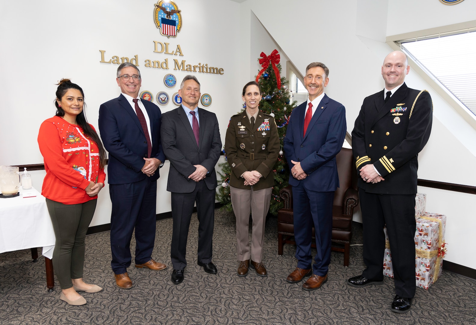Six people pose for photo in front of Christmas tree.