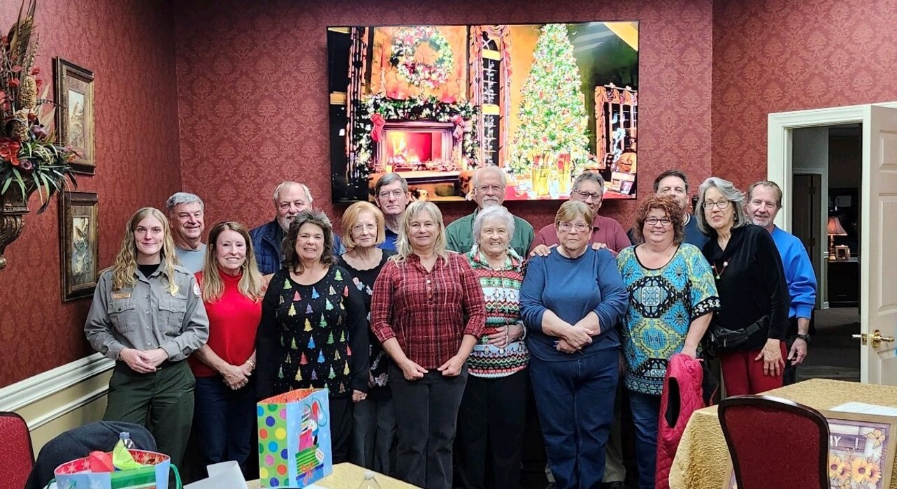 Group of people standing indoors facing the camera in two rows.