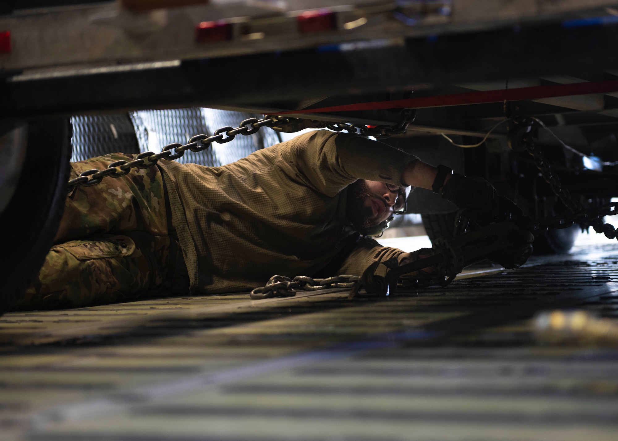 U.S. Air Force Senior Airmen Ameer Haddad, 22nd Airlift Squadron loadmaster, secures cargo inside the C-5M Super Galaxy at Joint Base Lewis-McChord, Wash., Dec. 8, 2023. The joint operation consisted of loading cargo and mini submersibles on the aircraft and was conducted by service members from Travis Air Force Base, Calif., Joint Base Pearl Harbor-Hickam, Hawaii, and JBLM. (U.S. Air Force photo by Airman 1st Class Megan Geiger)