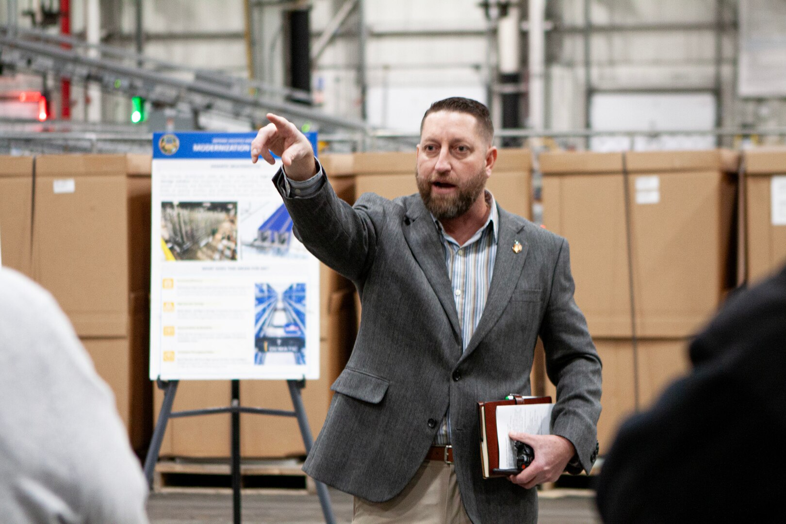 Man in a suit holding documents and pointing.
