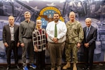 People standing in front of a Defense Logistics Agency logo mural.