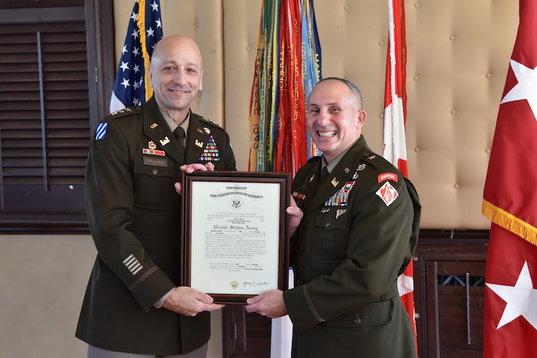 A man in an Army uniform holds a certificate with another man who is wearing an Army uniform.