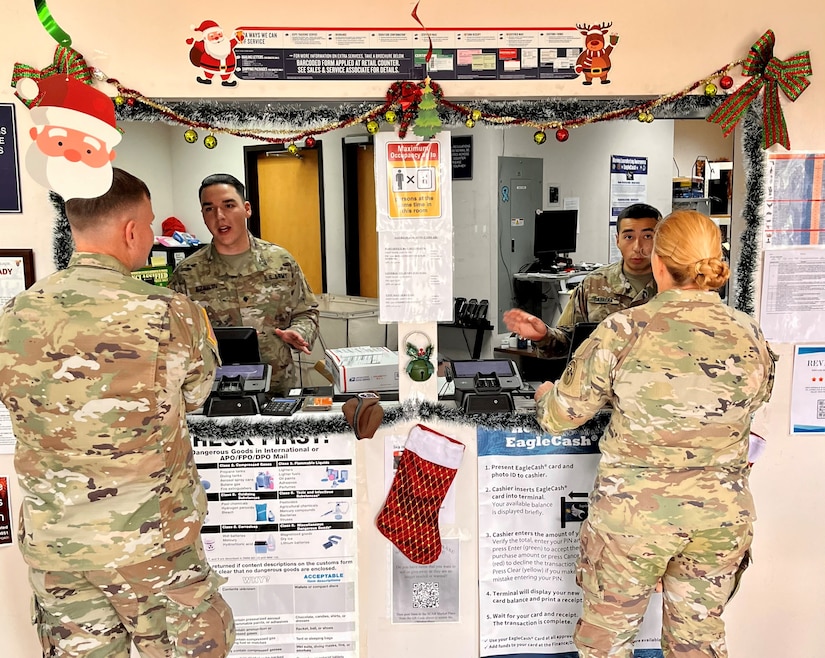 Spc. Gabriel Ezrilov (left), a financial clerk with the 909th HR Co. (Postal), speaks with a customer at the front window of the Soto Cano Post Office on Soto Cano Air Base near Comayagua, Honduras. The unit just kicked off a 9-month deployment providing postal operations at the air base.