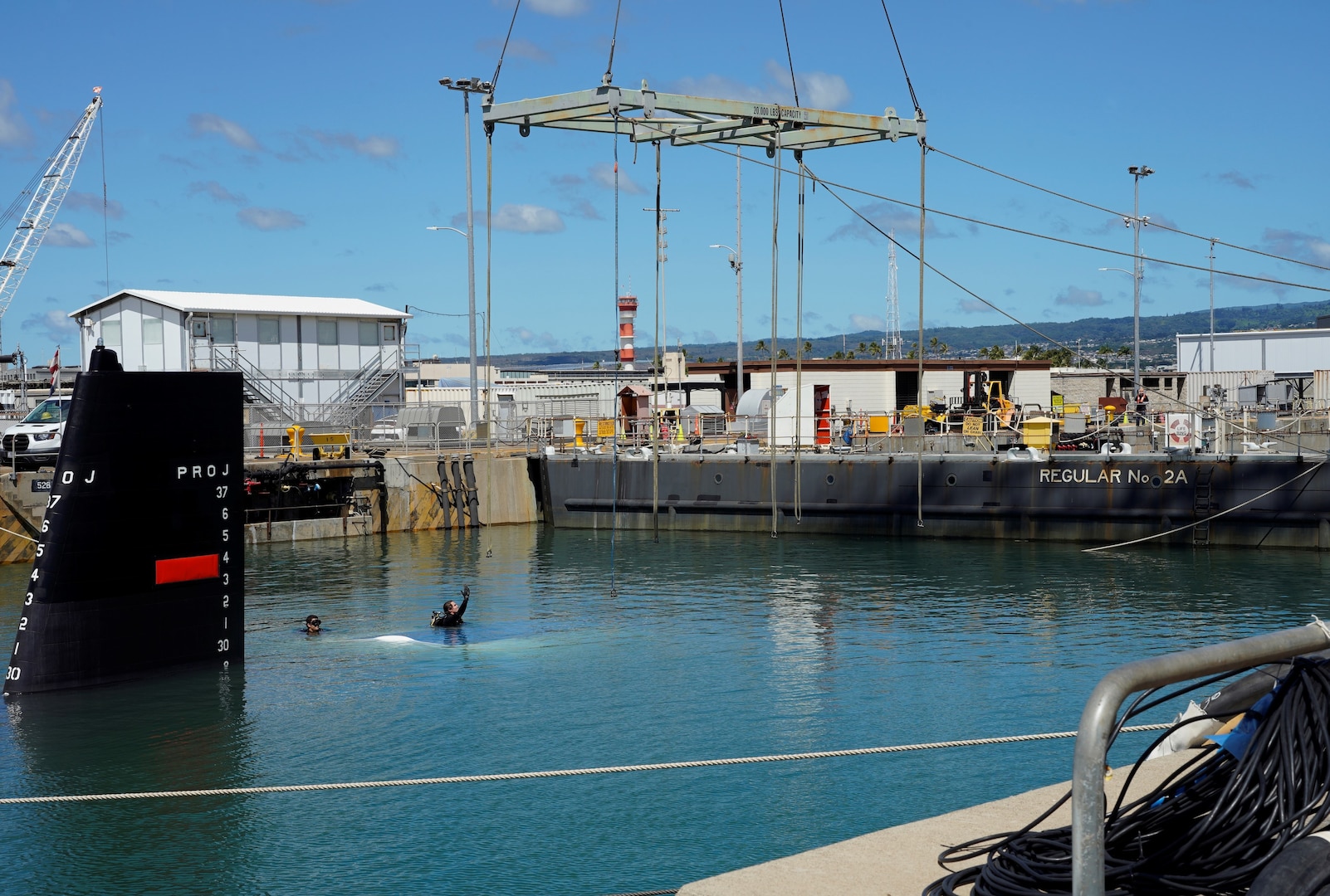 A Pearl Harbor Naval Shipyard & Intermediate Maintenance Facility diver directs rigging equipment into the water during the undocking of the Virginia-class attack submarine USS Minnesota (SSN 783) from Dry Dock 2, Oct. 12, 2023.