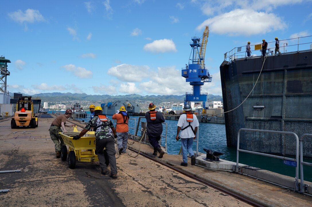 Pearl Harbor Naval Shipyard & Intermediate Maintenance Facility personnel assist in moving the caisson during the undocking of the Virginia-class attack submarine USS Minnesota (SSN 783) from Dry Dock 2, Oct. 12, 2023.