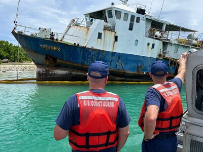 The U.S. Coast Guard captain of the port Guam zone explains to the U.S. Coast Guard 14th District commander the status of the pollution response on the motor vessel Voyager, a 116-foot Indonesian-flagged ship adjacent to Piti Channel following Typhoon Mawar, in Piti, Guam, in August 2023. By late November, the operation successfully recovered approximately 51,000 gallons of fuel oil mixture, around four cubic yards of oiled debris, and various hazardous substances from the M/V Voyager, prioritizing environmental safety and the likelihood of operational success. (U.S. Coast Guard photo by Lt. j.g. Whip Blacklaw)