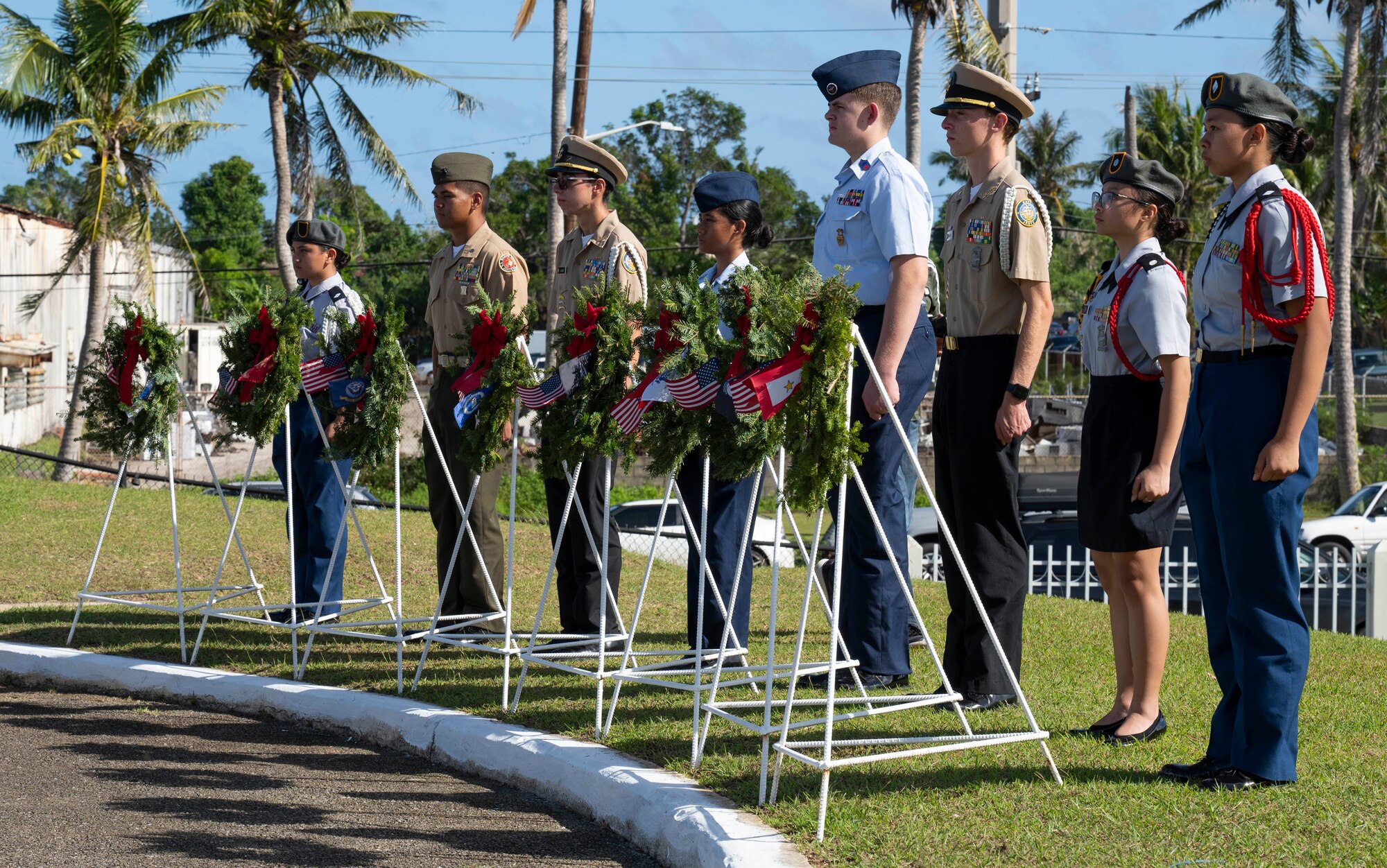 Junior reserve officer training corps members stand behind placed wreaths during the Wreaths Across America ceremony at the Guam Veterans Cemetery, Guam, Dec. 16, 2023. The Wreaths Across America program allows families to honor and remember the sacrifices of our military Veterans by placing wreaths on their graves during the holiday season. (U.S. Air Force photo by Airman 1st Class Spencer Perkins)